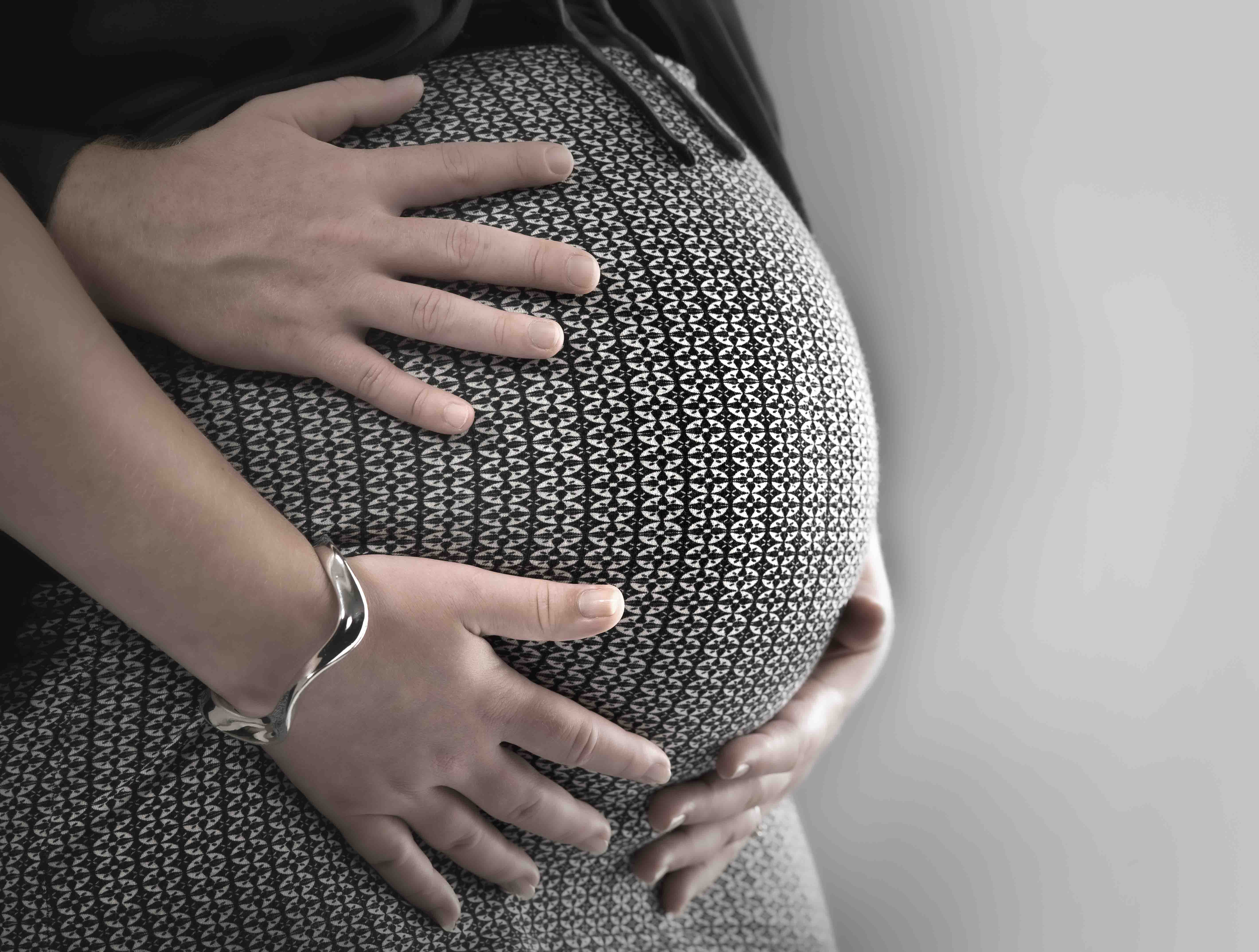 Zwangerschapsfotografie met partner, drie handen op zwangerschapsbuik close-up met een zwart met wit rokje gefotografeerd in fotostudio Rotterdam. www.marijnissenfotografie.nl