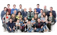 Fotoshoot familieportret groepsfoto van Opa en Oma met gezinnen eromheen van 26 personen zittend in witte omgeving gefotografeerd in fotostudio Rotterdam. www.marijnissenfotografie.nl