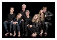 Grappige familiefoto, 5 kleinkinderen met Opa en Oma zittend in zwarte omgeving gefotografeerd in fotostudio Rotterdam. www.marijnissenfotografie.nl