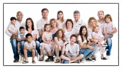 Familieportret van 18 personen zittend op de grond en op stoeltjes in witte omgeving gefotografeerd in fotostudio Rotterdam. www.marijnissenfotografie.nl