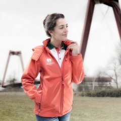 Foto gemaakt in greenscreen fotostudio waar een fotomodel een oranje jas van Laurens thuiszorg aan heeft ze kijkt net weg van de camera en staat voor de Willemsbrug in Rotterdam gefotografeerd door fotograaf fotostudio Marijnissen Fotografie Rotterdam.