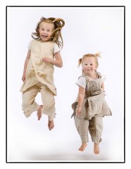 Kinderfotografie van 2 schattige zusjes die tegelijk in de luchtspringen en daar veel plezier in hebben gefotografeerd door fotograaf in de fotostudio. www.marijnissenfotografie.nl