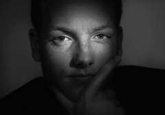 Close-up portret in film noir achtige stijl verlicht waardoor alleen de ogen goed te zien zijn gefotografeerd door fotograaf in de fotostudio. www.marijnissenfotografie.nl