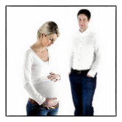 Zwangerschapsshoot met partner in spijkerbroek met wit shirt, man kijkt naar zwangerschapsbuik van vrouw met witte achtergrond gefotografeerd in fotostudio Rotterdam. www.marijnissenfotografie.nl